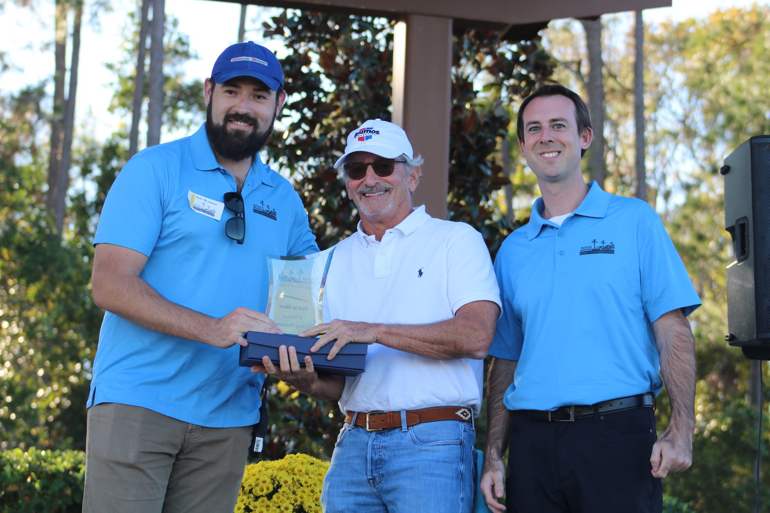 Jake Weisman and Justin Felker present Sam Joiner (center) with the 2021 Ponte Vedra Auto Show Best in Show Trophy in honor of Larry Weisman.